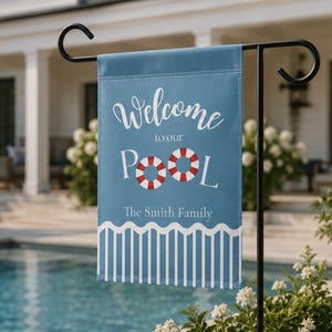 May include: A rectangular blue garden flag featuring the white text Welcome to our POOL with two red and white life preservers replacing the letter O. Below, the text The Smith Family appears above a white wavy line and vertical stripes.