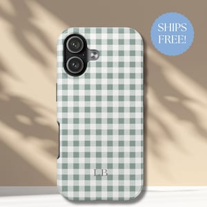 May include: A phone case featuring a green and white gingham design. The case has a dual-lens camera aperture and the initials "LB" at the base. A blue circle with the text "SHIPS FREE!" is in the upper right corner.