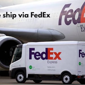 Pode incluir: Um avi&atilde;o de carga FedEx Express branco com marca roxa e laranja estacionado na pista. Em primeiro plano, um caminh&atilde;o de entrega FedEx Express branco com logotipos roxos e laranjas est&aacute; posicionado em frente ao grande motor a jato.