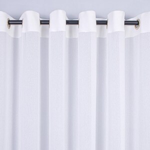 Pode incluir: Um painel de cortina branco com uma faixa superior branca s&oacute;lida e ilh&oacute;s met&aacute;licos espa&ccedil;ados uniformemente. A cortina est&aacute; pendurada numa vara horizontal escura e fina, criando pregas verticais e uma apar&ecirc;ncia texturizada semitransparente.