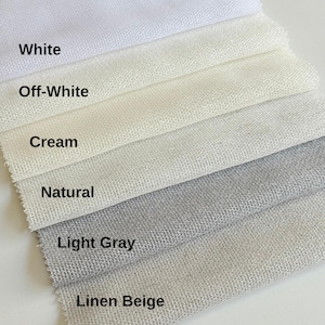 Pode incluir: Uma cole&ccedil;&atilde;o de amostras de tecido rotuladas como First Type Of Fabric, apresentando seis cores distintas dispostas em camadas: White, Off-White, Cream, Natural, Light Gray e Linen Beige. Cada amostra exibe uma textura tecida vis&iacute;vel e uniforme.