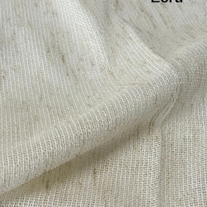 Pode incluir: Uma pe&ccedil;a de tecido na cor crua com uma textura tecida vis&iacute;vel e um padr&atilde;o de trama aberta e solta. O material apresenta manchas sutis de marrom claro por toda a superf&iacute;cie esbranqui&ccedil;ada. A palavra Ecru est&aacute; impressa em preto no canto.