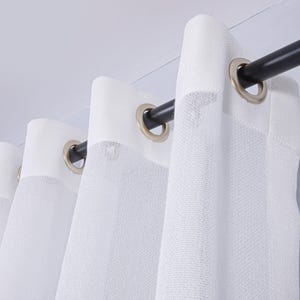 Pode incluir: Um painel de cortina branco semitransparente com um cabe&ccedil;alho refor&ccedil;ado apresentando ilh&oacute;s met&aacute;licos prateados espa&ccedil;ados uniformemente. A cortina est&aacute; suspensa numa barra cil&iacute;ndrica preta lisa, criando dobras verticais suaves e um aspeto transl&uacute;cido.