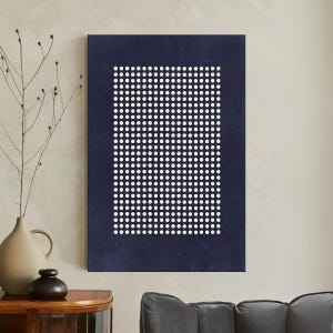 May include: A rectangular navy blue wall art piece with a grid of white dots. The dots are evenly spaced within a white border. The artwork is displayed on a neutral-colored wall, with a vase and decorative items in the foreground.