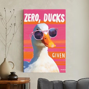 May include: A canvas print featuring a white duck wearing pink sunglasses. The duck has an orange beak and is set against a pink and orange striped background. The words "ZERO, DUCKS GIVEN" are printed in white.