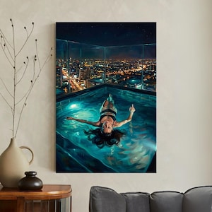 May include: A canvas print depicts a woman floating in a rooftop pool at night. The pool reflects the city lights and starry sky. The woman is wearing a black top and white bottoms. The artwork is displayed on a wall.