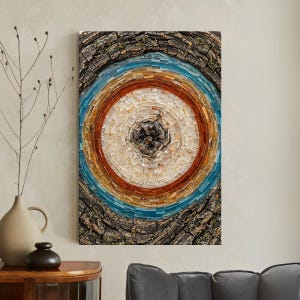 May include: A mosaic art piece featuring a circular design with concentric rings of color. The artwork incorporates a natural wood bark frame. The central design includes a dark, textured center surrounded by rings of white, orange, blue, and brown.