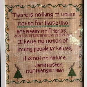 May include: A framed cross-stitch sampler on beige fabric featuring the text: There is nothing I would not do for those who are really my friends. I have no notion of loving people by halves, it is not my nature. - Jane Austen, Northanger Abbey.