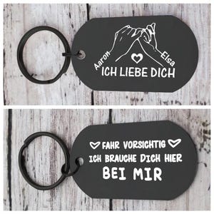 Può includere: Portachiavi in metallo nero con portachiavi nero. Il portachiavi ha un'etichetta ovale con testo bianco e una grafica di due mani che si tengono per il mignolo. Il testo dice "Aaron", "Elsa" e "ICH LIEBE DICH". Il secondo portachiavi dice "FAHR VORSICHTIG" e "ICH BRAUCHE DICH HIER BEI MIR".