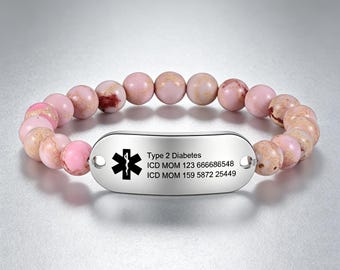 May include: A pink beaded bracelet with a silver medical ID tag. The tag has a medical symbol and text that reads "Type 2 Diabetes" and medical information. The beads are a mix of pink and light brown.