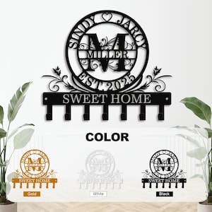 May include: A black metal key holder with the text "SWEET HOME" and hooks. The design includes a circular emblem with the names "SINDY JARC" and "MILLER EST 2025". Available in gold, white, and black.