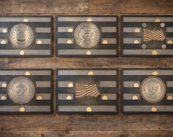 May include: Six wooden plaques with military and patriotic emblems. Each plaque has a dark gray frame with horizontal slats and gold-colored accents. The emblems include the US Air Force, Navy, and Marine Corps seals, and the American flag.