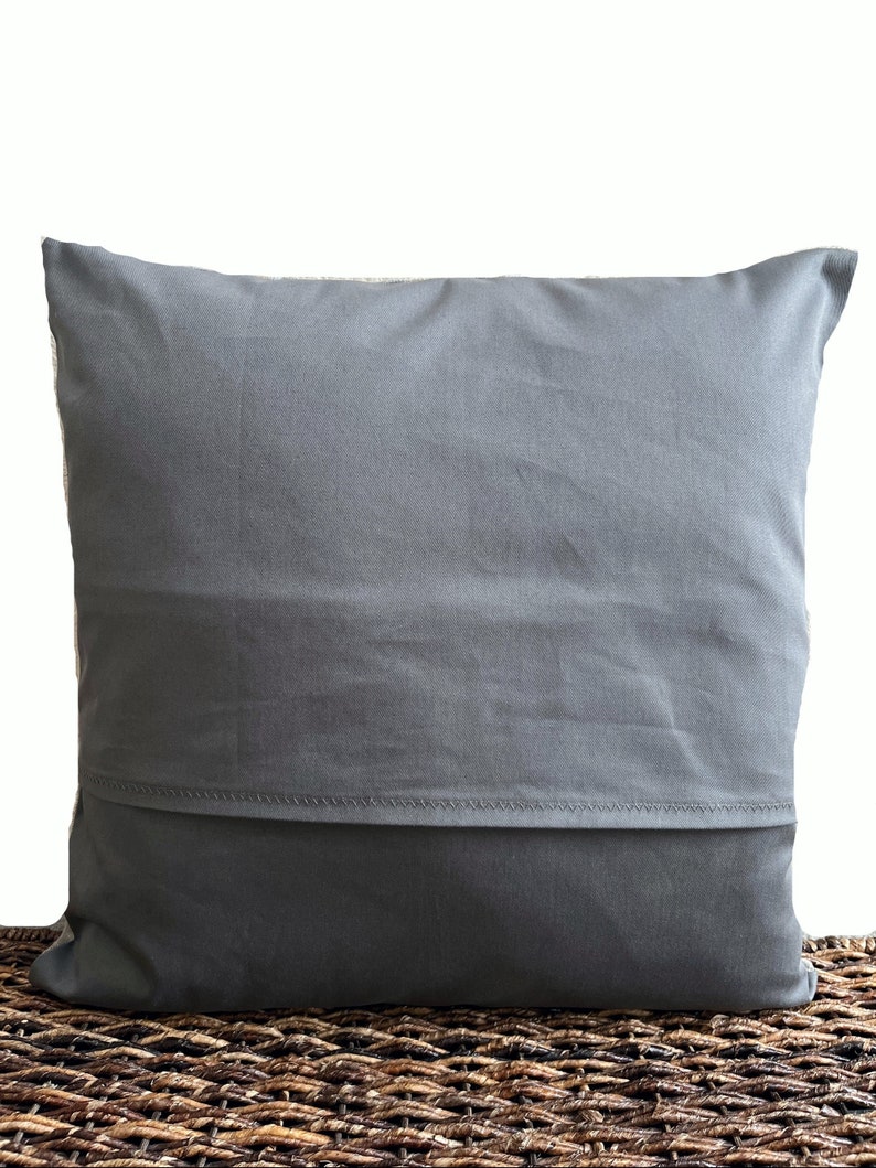 May include: A square throw pillow cover in a solid dark gray color. The cover features a horizontal envelope-style closure flap across the lower section, secured with visible stitching along the edge of the fabric fold, creating a clean finish.