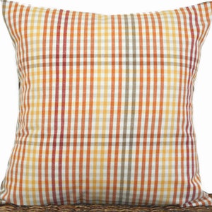 May include: A square throw pillow with a checkered pattern in shades of orange, red, brown, and white.