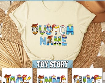 May include: Cream-colored t-shirt with the words "CUSTOM NAME" in colorful, cartoon-style letters. The shirt features a "Toy Story" theme, with additional text at the top and bottom. Below are three examples of names: JACK, EMMA, and MIKE.