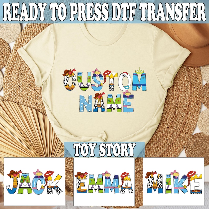 May include: Cream-colored t-shirt with the words "CUSTOM NAME" in colorful, cartoon-style letters. The shirt features a "Toy Story" theme, with additional text at the top and bottom. Below are three examples of names: JACK, EMMA, and MIKE.