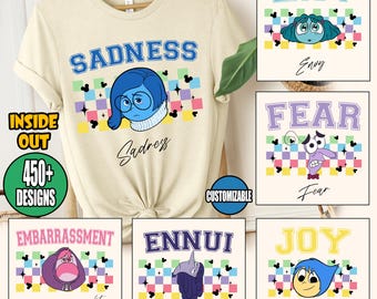 May include: A beige t-shirt with a graphic of the character Sadness from the movie Inside Out. The image also shows other designs with characters and text like "Envy", "Fear", "Embarrassment", "Ennui", and "Joy". The text "READY TO PRESS DTF TRANSFER" is at the top.