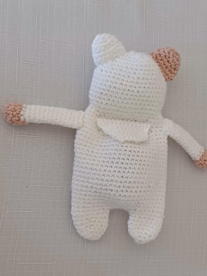 May include: White crocheted stuffed animal with pink ears and arms. The toy is in the shape of a bear.