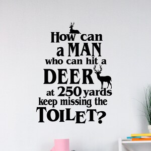 May include: Black and white text on a white wall that reads "How can a man who can hit a deer at 250 yards keep missing the toilet?"  A white toilet with a pink toilet paper roll is in the foreground.