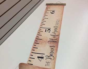May include: A brown and white growth chart with a ruler measuring up to 6 feet. The chart has a distressed look and the text "The Bean Holman Family" is printed on the right side.