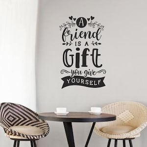 May include: A white ceramic mug with a black handle and the text "But First, Coffee" in a black, handwritten-style font. The mug is on a white surface.