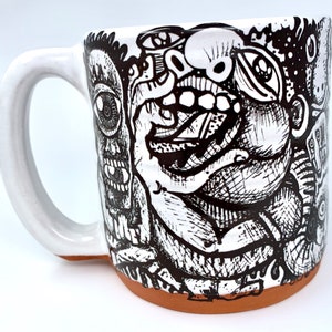 Puede incluir: Taza de cerámica blanca con una ilustración en blanco y negro de una cara con una gran boca abierta y varios diseños abstractos.