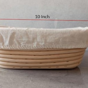Può includere: Un cesto di lievitazione per pane ovale di colore marrone chiaro con un rivestimento in lino bianco. Il cesto misura 25,4 cm di lunghezza e 8,4 cm di altezza.