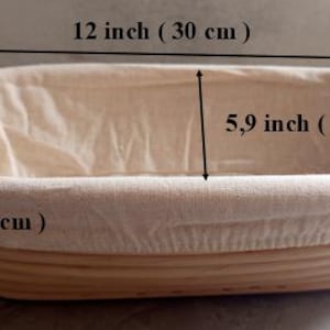 Może przedstawiać: Owalny kosz do wyrastania chleba, o długości 30 cm, szerokości 15 cm i wysokości 8 cm. Kosz wykonany jest z jasnego, tkanego materiału z wyjmowaną lnianą wkładką. Idealny do pieczenia chleba rzemieślniczego.