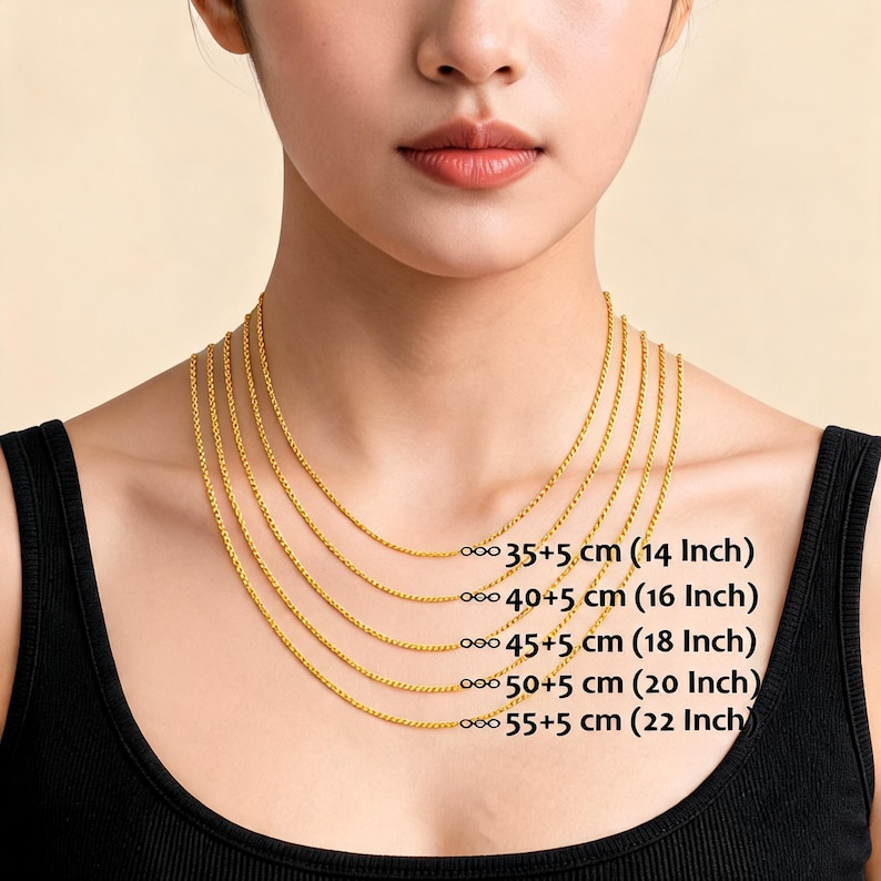 May include: A woman wearing a black top with multiple gold-colored chain necklaces of varying lengths. The necklaces are labeled with their lengths in centimeters and inches: 14, 16, 18, 20, and 22 inches.