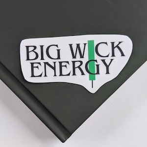 May include: White sticker with the text "BIG WICK ENERGY" in black lettering. A green vertical line is next to the word "WICK".