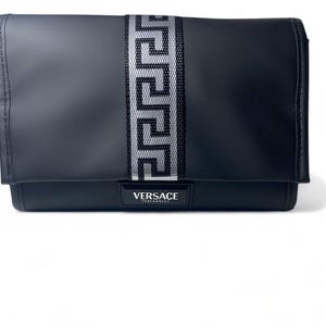 Puede incluir: Clutch negra con una franja central plateada y negra estampada. El clutch tiene un cierre de solapa y una pequeña etiqueta rectangular en la parte inferior con el texto "VERSACE FRAGRANCES".