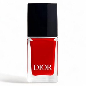 May include: A bottle of red nail polish with a black cap. The clear glass bottle has the word "DIOR" printed in white. The nail polish is a vibrant, solid red color.