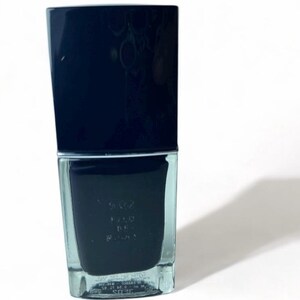 May include: A dark navy blue nail polish bottle with a rectangular shape and a matching cap. The bottle is on a white background, casting a shadow to the right. The nail polish is a deep, opaque color.