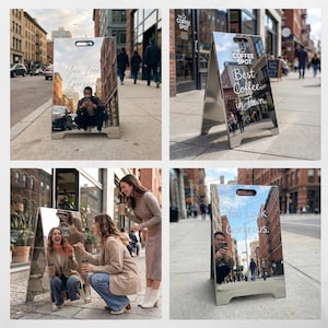 May include: A-frame sidewalk sign with a reflective surface. One sign reads "You Look Gorgeous." The other says "Best Coffee in Town." The signs are silver and have a handle at the top. The signs are placed on a city sidewalk.