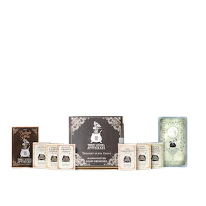 May include: A set of handcrafted soap bars with various scents, including Blood Orange Ginger, Lemon Lime, and Grapefruit. The soaps are packaged in a box with a black and gold design and the text "Three Sisters Apothecary Twilight in the Grove Handcrafted Soap Grimoire".