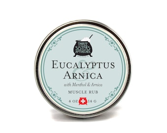May include: A silver tin with a blue and white label that reads "Three Sisters Apothecary" and "Eucalyptus & Arnica Muscle Rub with Menthol & Arnica". The tin is 4 oz or 14 g.