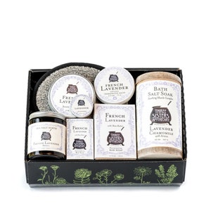 May include: A gift set featuring French Lavender products from Three Sisters Apothecary. The set includes a sea salt scrub, body butter, lip balm, bar soap, and bath salt soak. The products are packaged in a black box with floral designs.