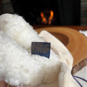 Pode incluir: Um close-up de um brinquedo de pel&uacute;cia creme com uma etiqueta azul. A etiqueta diz "THE BOYDS COLLECTION LTD" e inclui texto sobre Gettysburg, PA, e a s&eacute;rie Archive. O brinquedo de pel&uacute;cia &eacute; macio e fofo.