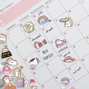 May include: A monthly planner with a calendar grid featuring cute hedgehog illustrations. The planner has a pink and white color scheme and includes motivational phrases like "I'll do my best!" and "Treat yourself!"