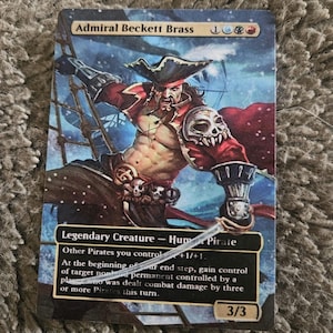 May include: A Magic: The Gathering card featuring Admiral Beckett Brass, a Human Pirate with a skull and crossbones on his arm. The card is blue, white, and red with a snowy background. The text on the card reads: "Admiral Beckett Brass, Legendary Creature - Human Pirate, Other Pirates you control +1/+1, At the beginning of your end step, gain control of target nonland permanent controlled by a player who was dealt combat damage by three or more Pirates this turn. 3/3."