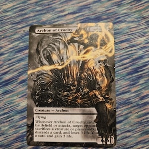 May include: A black and white Magic: The Gathering card featuring an illustration of a creature with glowing wings. The card text reads "Archon of Cruelty" and describes the creature's abilities.