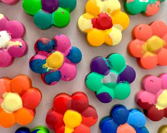 May include: Assortment of colorful, handmade crayon flower shapes. Each flower has a unique swirl pattern and is made with different shades of red, yellow, blue, green, and purple.