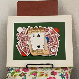 May include: A vintage green and red poster with a card game illustration. The poster features two playing cards, a pair of deuces, and the text "It is better to be a deuce in the same than a King in the discard."