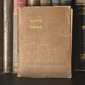 May include: A vintage copy of "Scott's Ivanhoe" with a brown cover. The title is in gold lettering within a rectangular frame. The book is part of the "Macmillan's Pocket Classics" series and is displayed among other books.