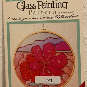Peut inclure: Un mod&egrave;le de peinture sur verre repr&eacute;sentant un motif floral tropical avec une fleur d'hibiscus rose. Le mod&egrave;le est intitul&eacute; "Glass Painting Pattern" et comprend le texte "Create your own Original Glass Art". Le num&eacute;ro du mod&egrave;le est 809. Le mod&egrave;le est de Plaid.