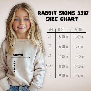 May include: A young girl smiles next to a size chart for Rabbit Skins 3317 apparel. The chart lists sizes 2T to 7T, with length and width measurements in inches. The text "Rabbit Skins 3317 Size Chart" is at the top.