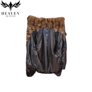 May include: A dark brown jacket with a fur collar and trim. The jacket's interior is a dark, shiny fabric, and it has two large pockets. The jacket is displayed against a white background.