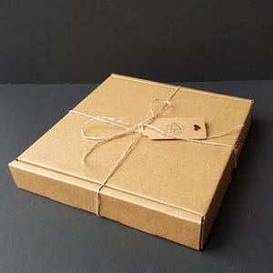 May include: A brown cardboard box with a string tied around it and a small brown tag that says "With Love From" with a heart.