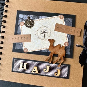 May include: A brown scrapbook with a black border and a compass design. The scrapbook has the words "HAJJ", "MAKKAH", and "MADINAH" on it. There is a camel silhouette on the cover.