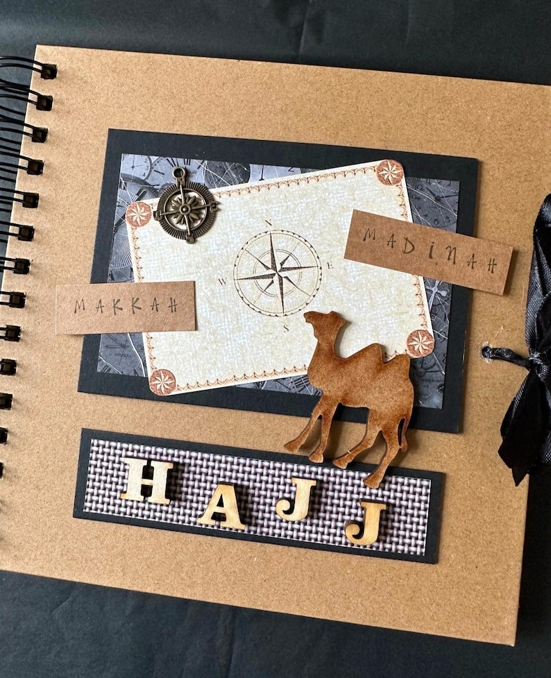 May include: A brown scrapbook with a black border and a compass design. The scrapbook has the words "HAJJ", "MAKKAH", and "MADINAH" on it. There is a camel silhouette on the cover.